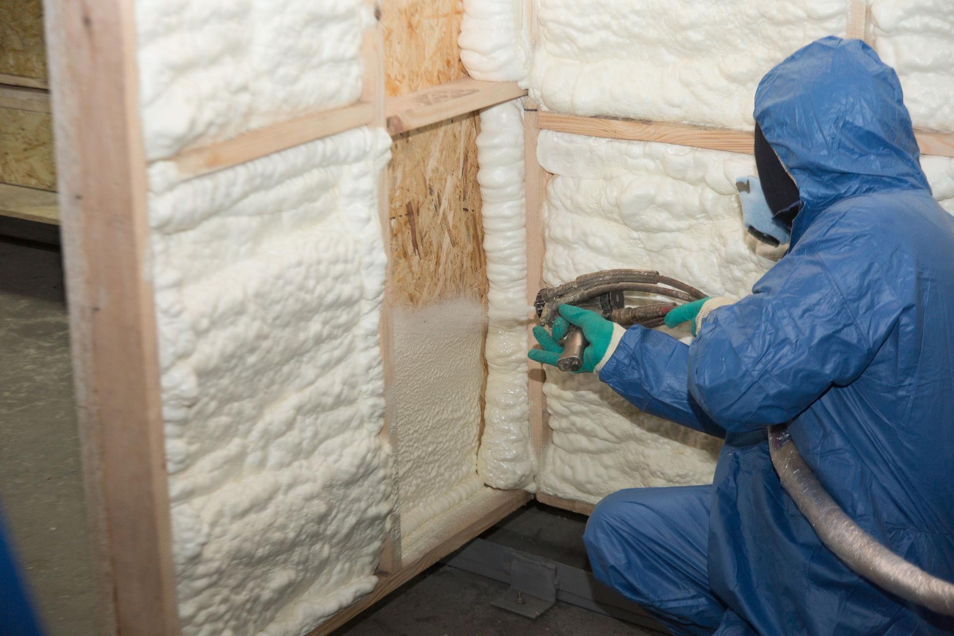 The worker insulates the walls of the house with spray foam insulation